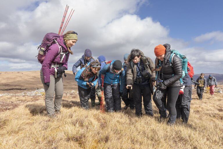 A group of people gather round on a grassy hill
